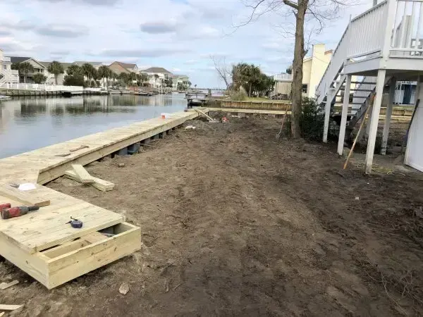 New timber seawall cap along a Cherry Grove channel lot beside the home’s stairs