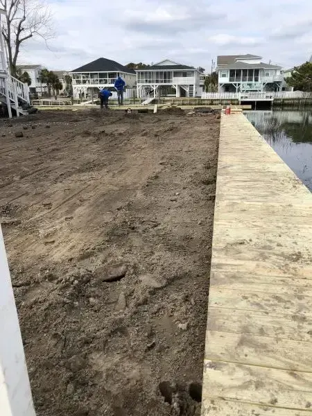 Close view along the timber seawall cap with the Cherry Grove channel on the right