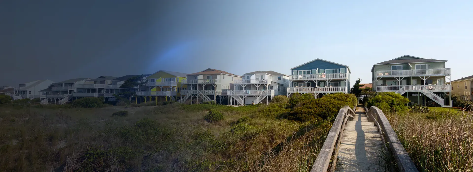 Wooden dune walkover leading from coastal homes toward the beach