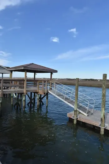 Metal-roof covered pierhead, railed gangway and floating dock beside the creek in Garden City, SC