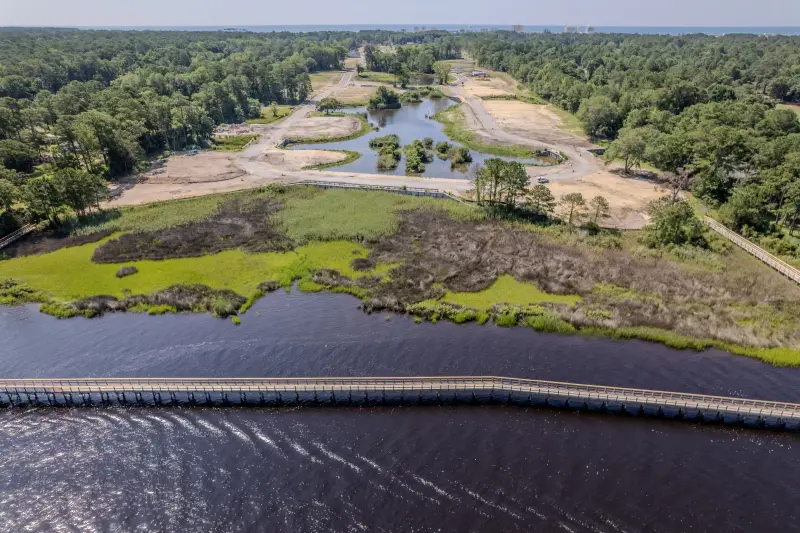 Drone view across the Hope Pointe pier toward the development site, roads, ponds and trees