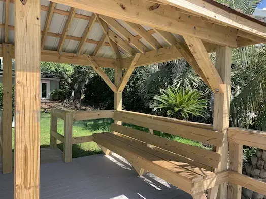 Timber roof framing and built-in bench beneath the metal roof of the Murrells Inlet pierhead