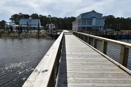 Timber pedestrian bridge with horizontal cable railings over a pond at Living Dunes at 82nd in Myrtle Beach