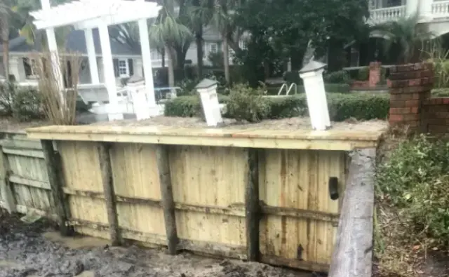 Repaired timber bulkhead and new cap at Allen McCall’s Sunset Beach property, with a white pergola behind the wall