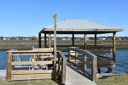 Timber walkway approaching the repaired pierhead and new metal roof beside a Garden City Beach creek