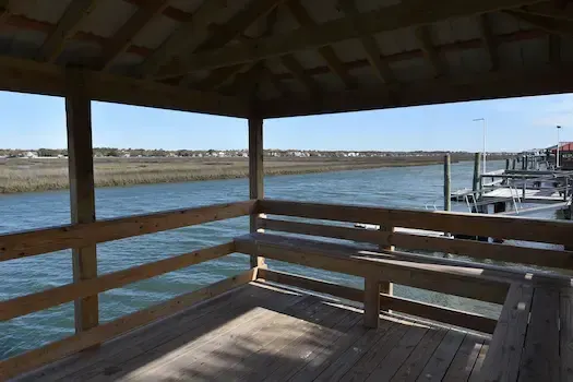 Bench seating under the pierhead roof overlooking the Garden City Beach creek