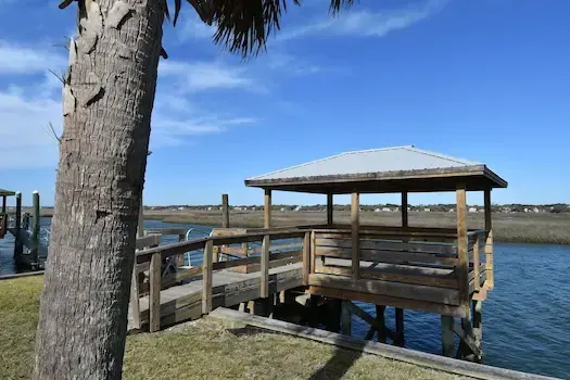 Covered pierhead and approach beside a palm tree on the Garden City Beach property