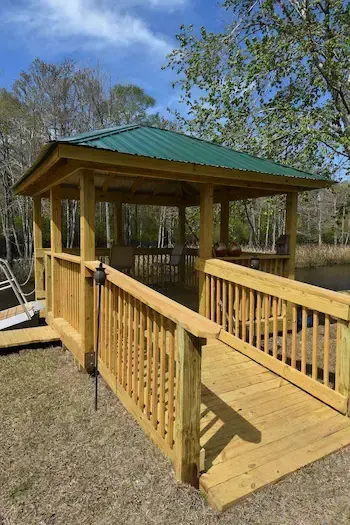 Timber walkway and railings leading into a covered pierhead with a green metal roof on the Waccamaw River