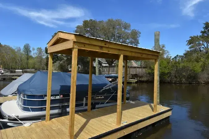 Timber-framed covered floating dock beside a boat at Wacca Wache Marina